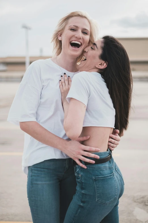 a couple of women standing next to each other, a photo, trending on pexels, happening, lesbian embrace, laughing maniacally, with pale skin, wearing pants and a t-shirt
