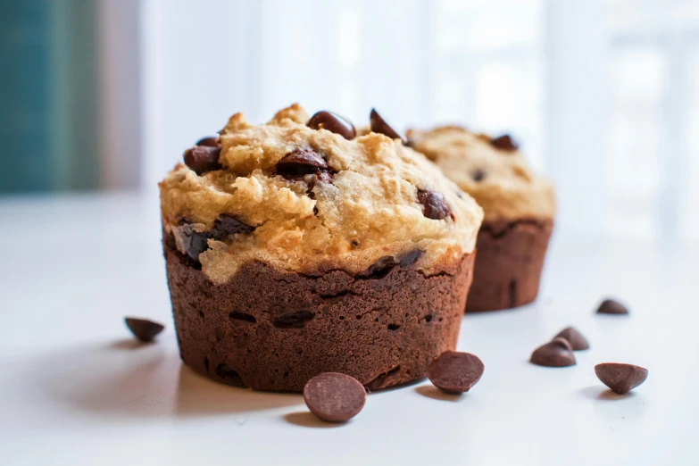 a couple of muffins sitting on top of a table, looking to the side off camera, chocolate, thick lining, full-size