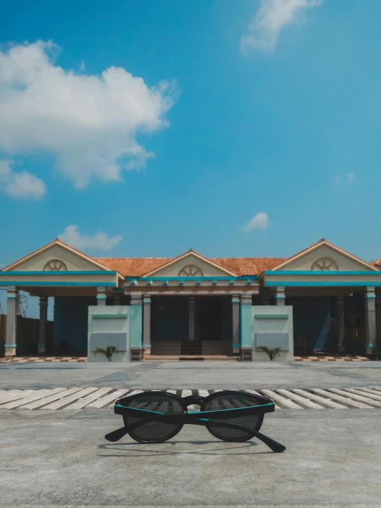 a pair of sunglasses sitting in front of a building, arsitektur nusantara, cinematic smooth unreal engine, brown and cyan blue color scheme, taken with sony alpha 9