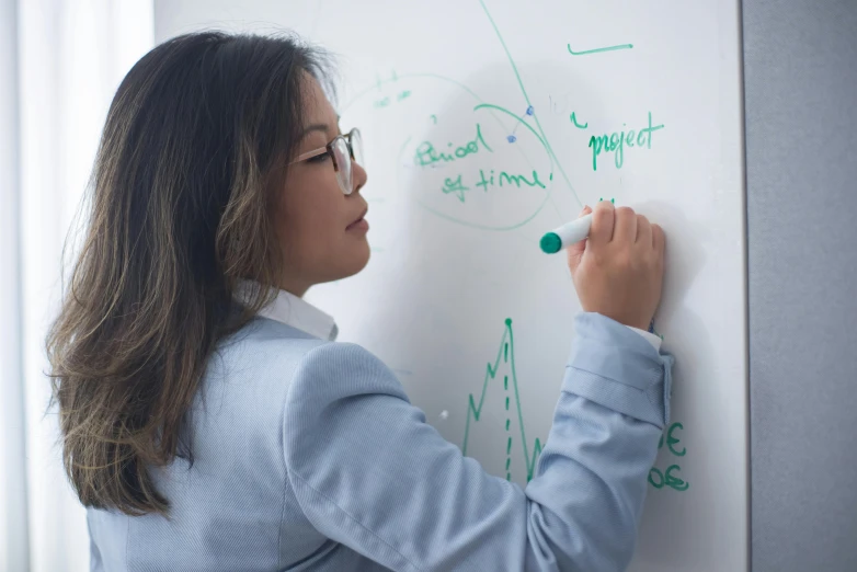 a woman is writing on a white board, pexels contest winner, balancing the equation, gemma chen, profile picture, technical