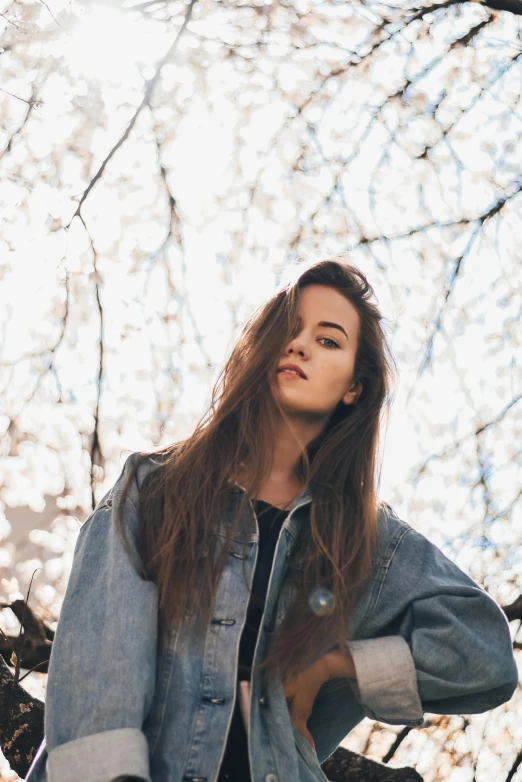 a woman standing in front of a cherry tree, inspired by Elsa Bleda, pexels contest winner, wearing a jeans jackets, young woman with long dark hair, profile image, mackenzie foy