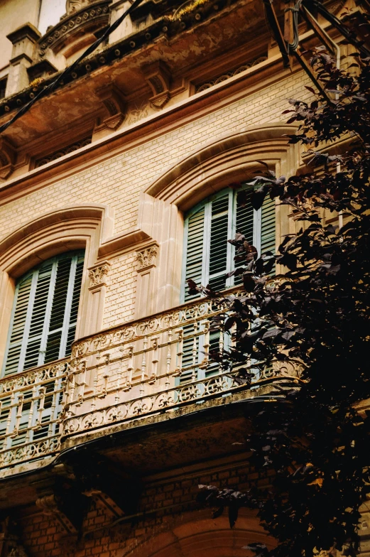 a tall building with a clock on the front of it, inspired by Tomàs Barceló, pexels contest winner, art nouveau, balcony door, massive trees with warm windows, analogue photo low quality, terracotta