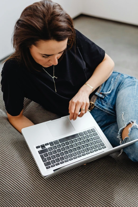 a woman sitting on the floor using a laptop, trending on pexels, wearing a dark shirt and jeans, bottom angle, avatar image, detailing