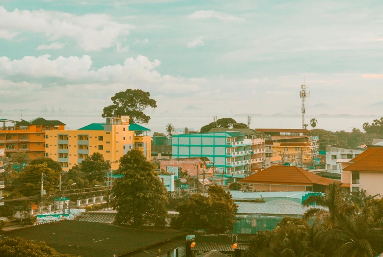 a view of a city from the top of a hill, a colorized photo, unsplash, sumatraism, yellow and cyan color palette, small town, background image