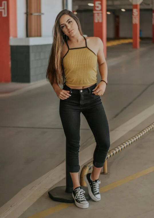 a woman standing on a skateboard in a parking garage, inspired by Sydney Carline, trending on unsplash, wearing yellow croptop, black denim pants, halter neck, view(full body + zoomed out)