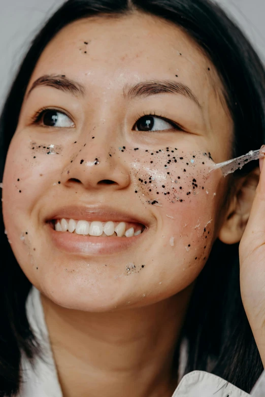 a woman with black spots on her face, trending on pexels, joy ang, textured base ; product photos, having fun, glomy