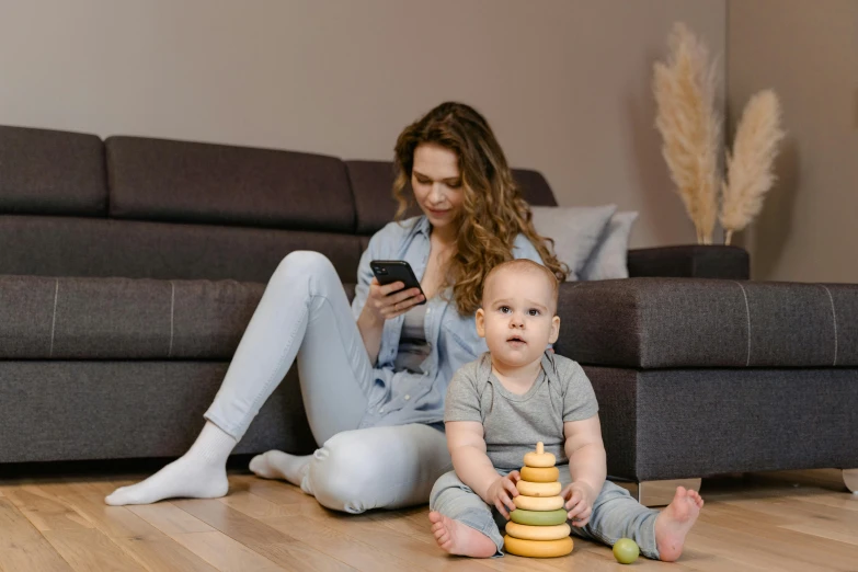 a woman sitting on the floor next to a baby, pexels contest winner, mobile game, at the sitting couch, thumbnail, stacked image