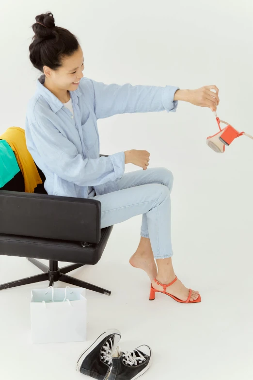 a woman sitting in a chair playing with a kite, by Jan Tengnagel, minimalism, jean and multicolor shoes, sustainable materials, pale blue outfit, official product image