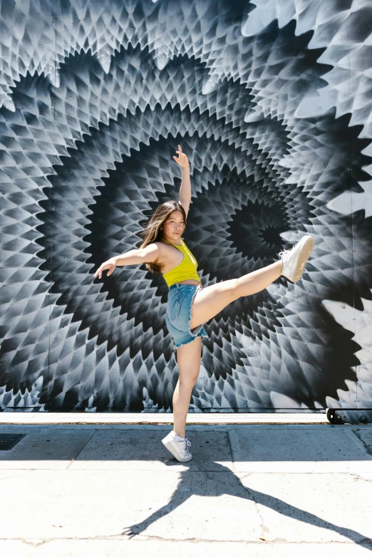 a woman is dancing in front of a mural, inspired by Elizabeth Polunin, pexels contest winner, kinetic art, spiral, felipe pantone, casual pose, low quality photo