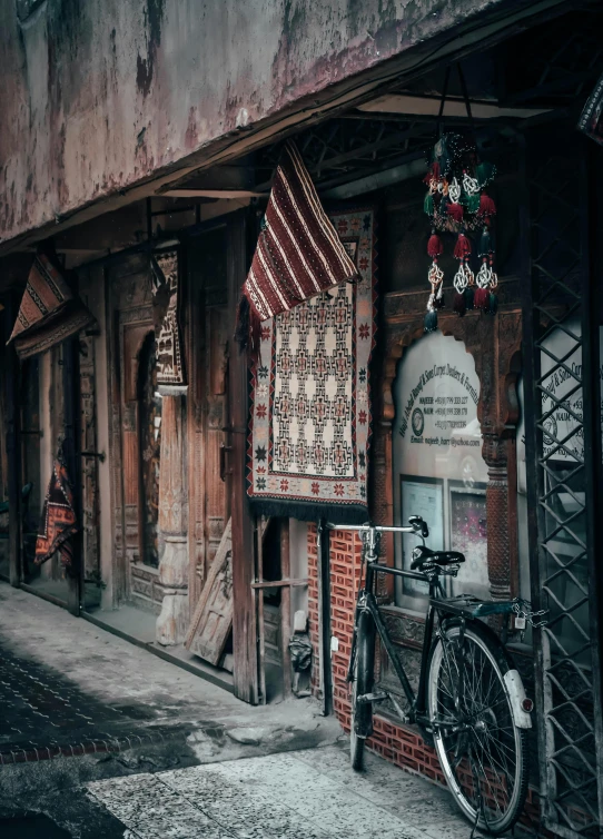 a bicycle is parked in front of a building, inspired by Steve McCurry, pexels contest winner, graffiti, inside an arabian market bazaar, detailed carved ornaments, old color photo, old asian village