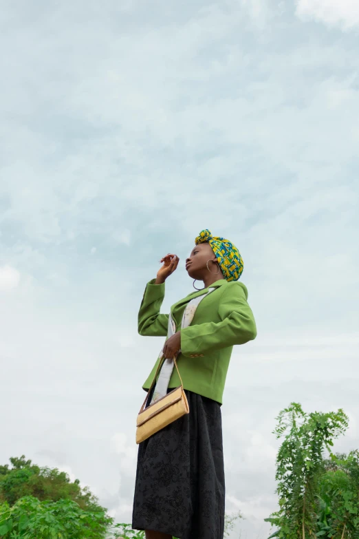 a woman standing on top of a lush green field, by Chinwe Chukwuogo-Roy, happening, taking a smoke break, lemonade, holding a gold bag, looking to the sky