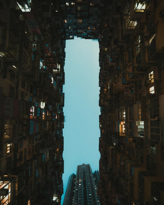 a tall building in the middle of a city at night, an album cover, by Patrick Ching, unsplash contest winner, perfect symmetrical image, in the middle of a small colony, head looking up, view from inside