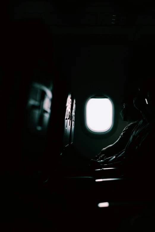 a person sitting in an airplane looking out the window, by Adam Chmielowski, dark ambient, eerie person silhouette, sittin, lofi