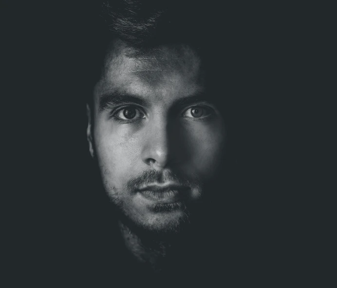 a black and white photo of a man's face, a black and white photo, by Adam Marczyński, pexels contest winner, massurrealism, young spanish man, alternate album cover, vantablack chiaroscuro, blue-eyed man