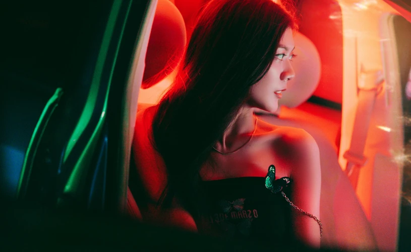 a woman sitting in a car looking out the window, an album cover, inspired by Elsa Bleda, pexels contest winner, gorgeous chinese model, butterfly lighting, red green, 3 d neon art of a womens body