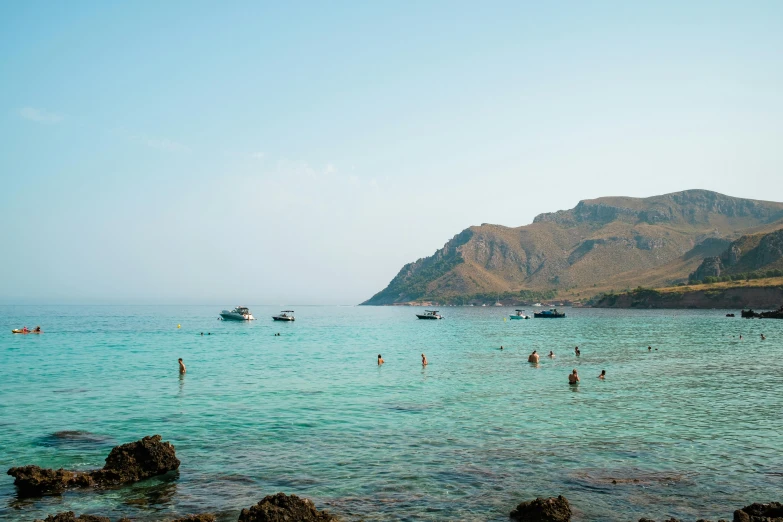 a group of people swimming in a body of water, les nabis, in socotra island, boats in the water, distant photo, unsplash photography