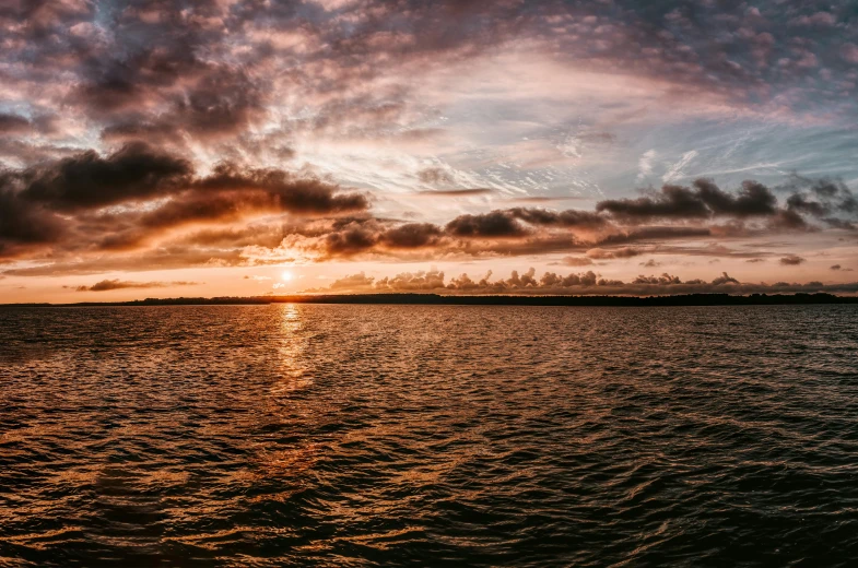 the sun is setting over a body of water, pexels contest winner, wide panoramic shot, pembrokeshire, fan favorite, sunset clouds