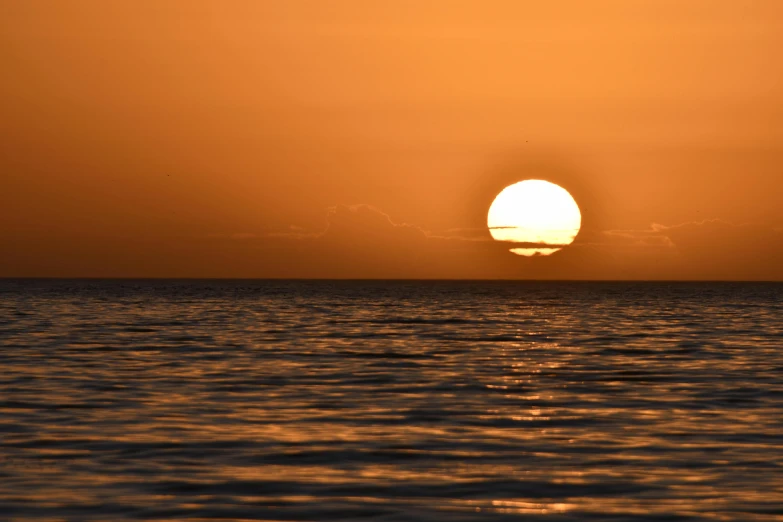 the sun is setting on the horizon of the ocean, a picture, by Jan Tengnagel, pexels, orange, heat shimmering, no cropping, paradise