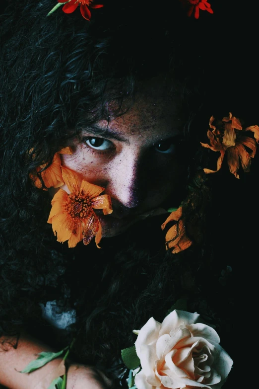 a close up of a person with flowers in their hair, an album cover, inspired by Elsa Bleda, pexels contest winner, renaissance, with haunted eyes and curly hair, in a black room, yellow - orange eyes, woman made of plants