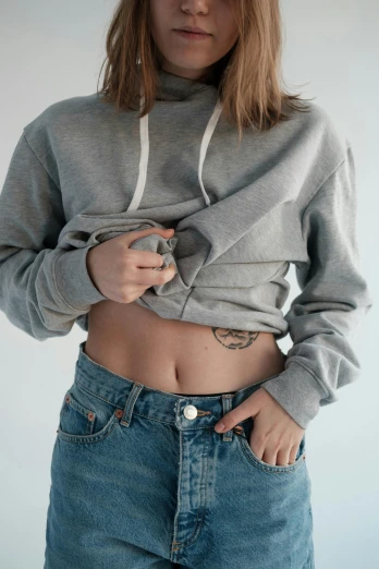 a woman with a tattoo on her stomach, trending on pexels, grey hoodie opened, exposed midriff, 👅 👅, ( ( ( wearing jeans ) ) )