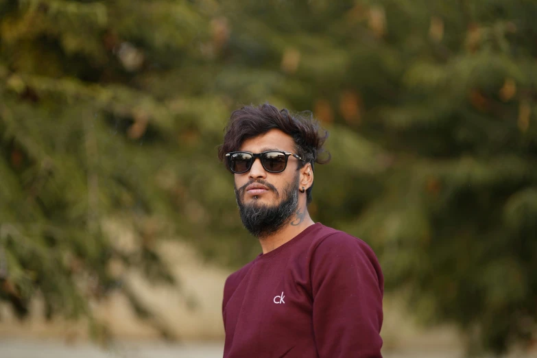 a man with a beard and sunglasses holding a skateboard, pexels contest winner, hurufiyya, he is wearing a brown sweater, avatar image, indian, professional profile picture