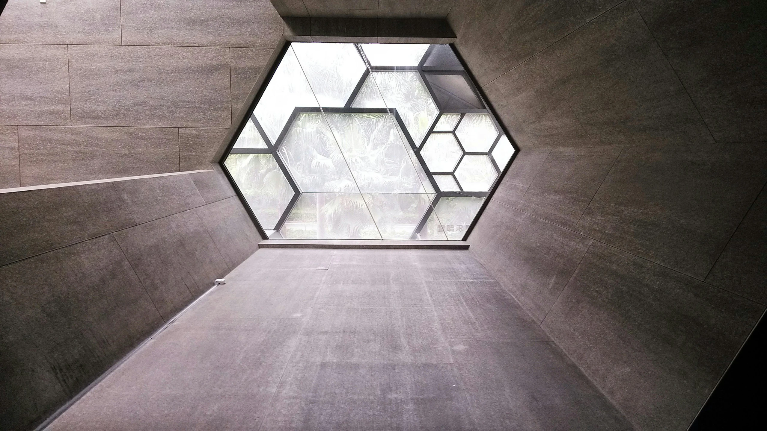 the inside of a building with a hexagonal window, inspired by Buckminster Fuller, light and space, mausoleum, architectural finishes, modular graphene, concrete _ wall ) ]