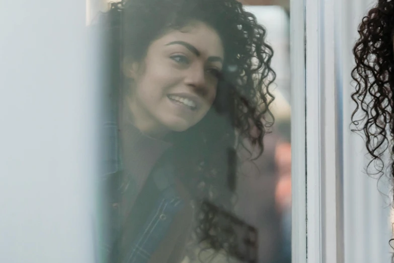 a woman with curly hair looking out of a window, charli bowater and artgeem, welcoming grin, zoomed in shots, more reflection