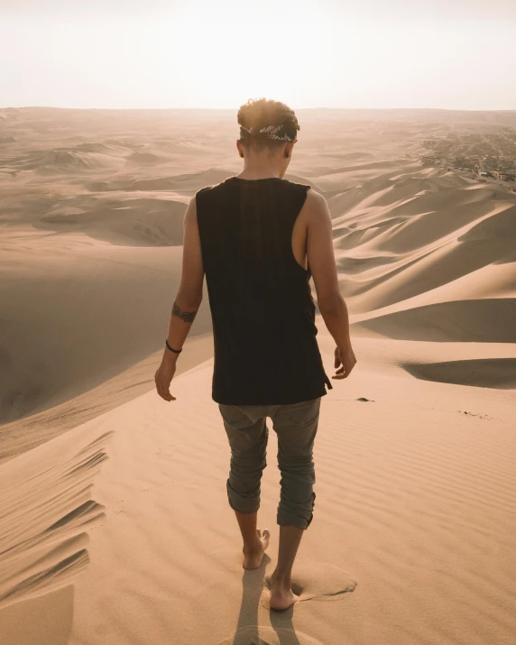 a man walking on a sand dune in the desert, trending on pexels, an epic non - binary model, wearing a vest top, pathetic, looking out the window