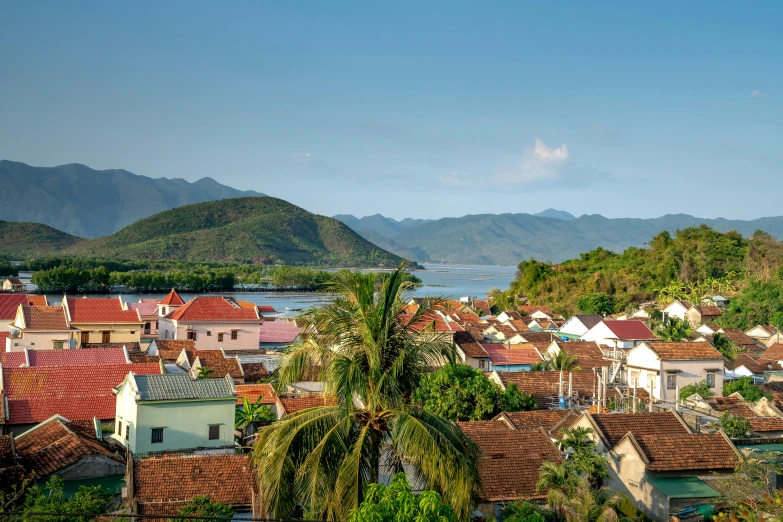 a view of a town with mountains in the background, pexels contest winner, happening, tropical location, avatar image, white buildings with red roofs, nuttavut baiphowongse