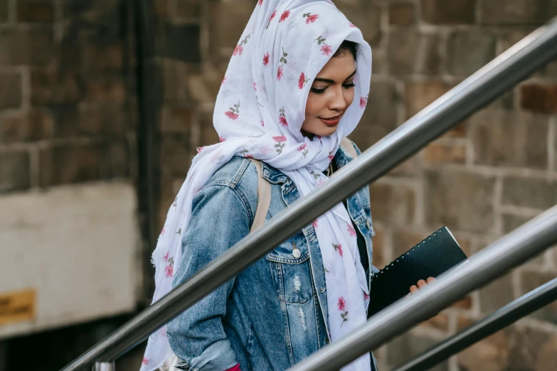 a woman wearing a hijab and carrying a book, trending on unsplash, wearing double denim, wearing pink floral chiton, white scarf, student