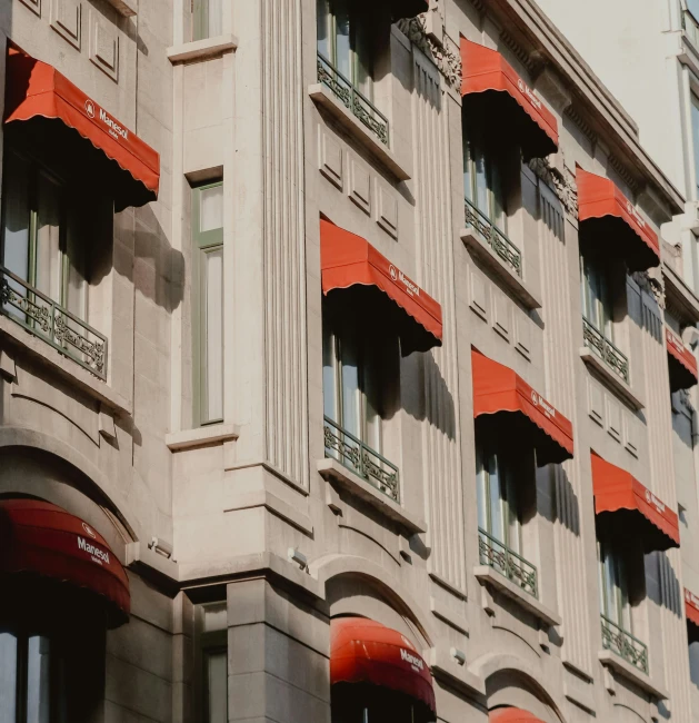 a tall building with red awnings in front of it, inspired by Albert Paris Gütersloh, pexels contest winner, art nouveau, orange details, hotel room, directoire style, conde nast traveler photo