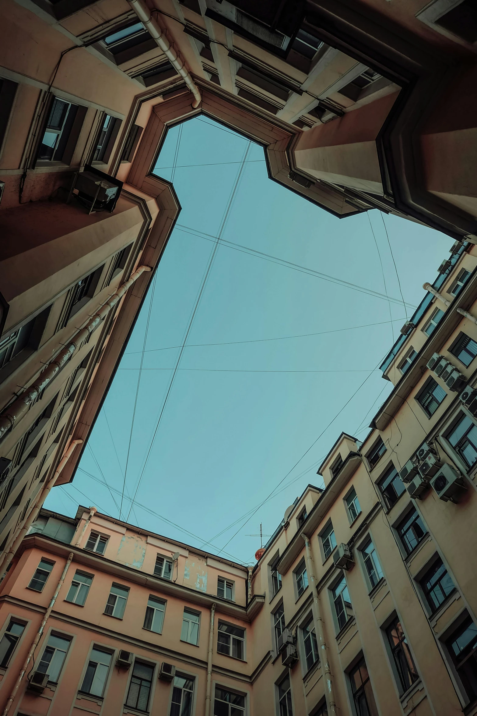 a very tall building with a blue sky in the background, an album cover, inspired by Alexander Rodchenko, unsplash contest winner, hyperrealism, tangled wires, post - soviet courtyard, view from the streets, saint petersburg