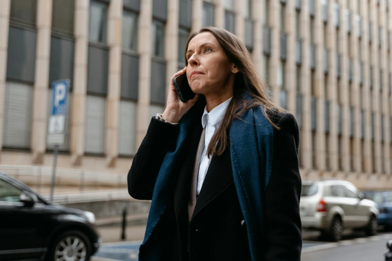 a woman walking down a street talking on a cell phone, by Emma Andijewska, pexels contest winner, lawyer suit, looking serious, female lead character, kirsi salonen