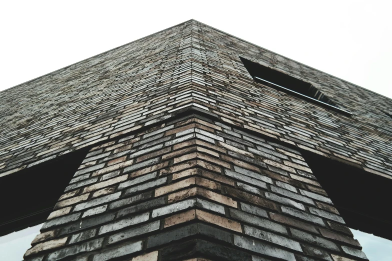 a tall brick building with a sky in the background, inspired by Peter Zumthor, unsplash, angled shot, slate, brown, diagonal