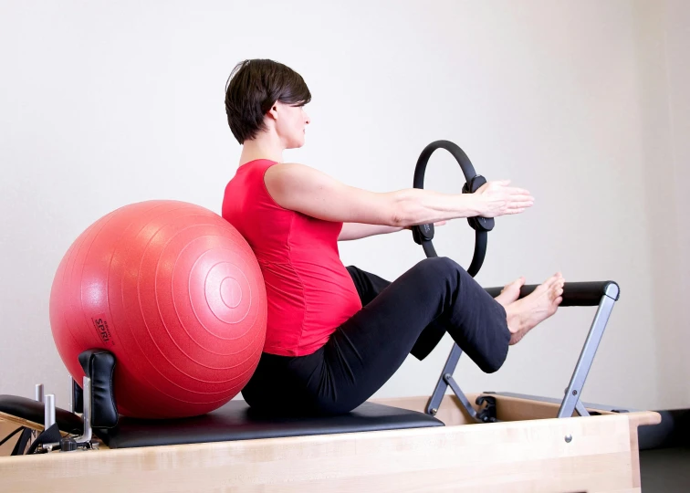 a woman sitting on a pilates with a red ball, private press, swanland, no - text no - logo, half body photo