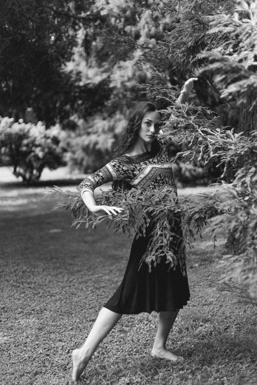 a black and white photo of a woman throwing a frisbee, inspired by Max Dupain, arabesque, covered in plants, li bingbing, next to a tree, wearing a dress made of vines