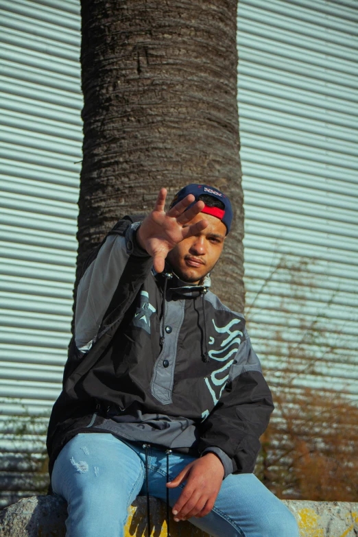 a man sitting on a bench next to a palm tree, an album cover, unsplash, graffiti, doing a sassy pose, wearing a track suit, headshot profile picture, middle finger