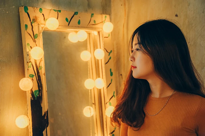 a woman standing in front of a mirror, inspired by Elsa Bleda, trending on pexels, realism, cute korean actress, warm yellow lights, vietnamese woman, 18 years old