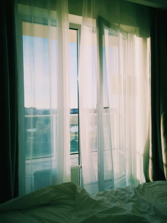 a bed sitting in a bedroom next to a window, a polaroid photo, inspired by Elsa Bleda, trending on unsplash, curtain, rinko kawauchi, sunny day, window ( city )