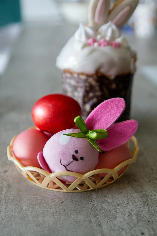 a basket filled with easter eggs next to a cupcake, a pastel, inspired by Rudolf von Alt, covered with pink marzipan, order, felt, medium close up