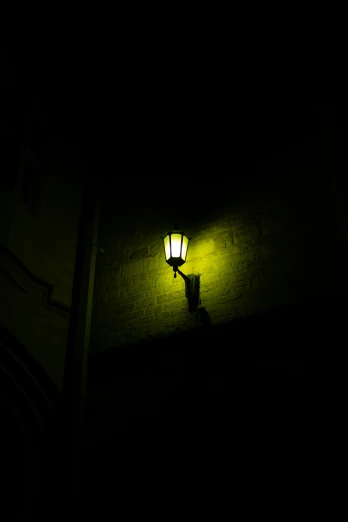 a street light lit up in the dark, by Andries Stock, light yellow, pale green glow, gothic lighting, yellow