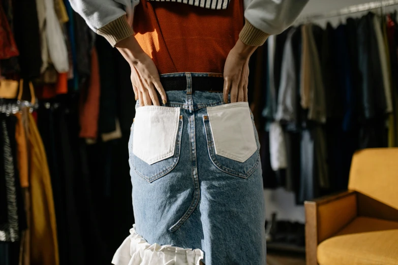 a woman standing in front of a rack of clothes, inspired by Elsa Bleda, trending on pexels, cute huge pockets hardware, dressed in a frilly ((ragged)), back view. nuri iyem, quirky shops