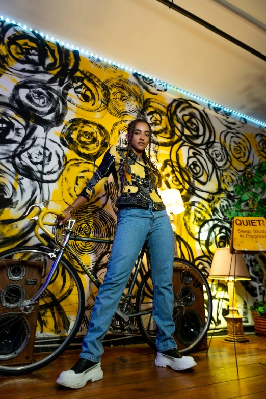 a woman standing next to a bicycle in a room, a portrait, trending on pexels, graffiti, black and yellow, denim, ashteroth, nigth