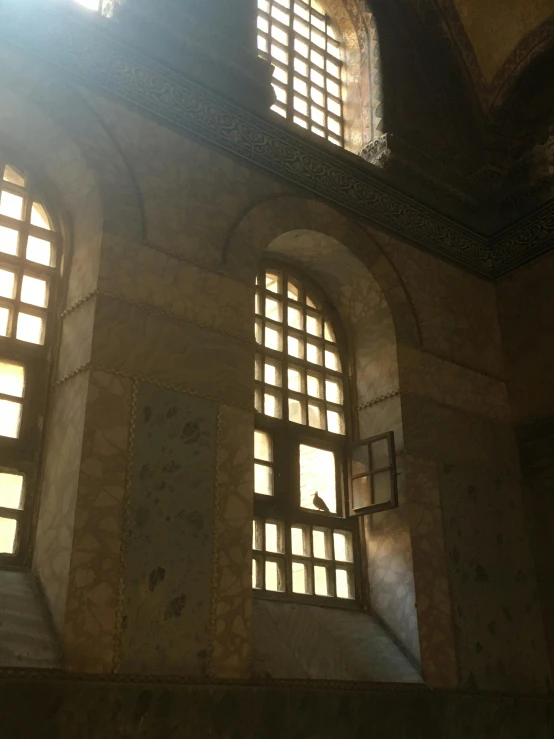 the sun shines through the windows of an old building, a mosaic, trending on unsplash, arabesque, low quality photo, in giza, museum photo, marble and wood and glass