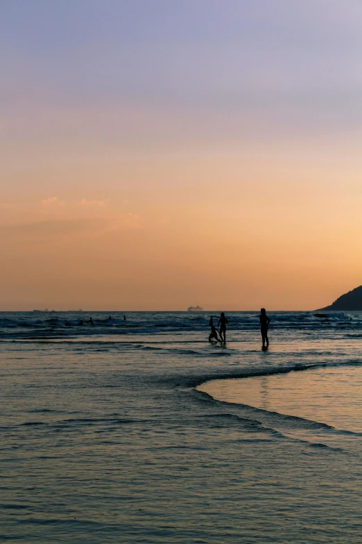 a couple of people standing on top of a beach next to the ocean, during a sunset, guangjian, rectangle, uncropped