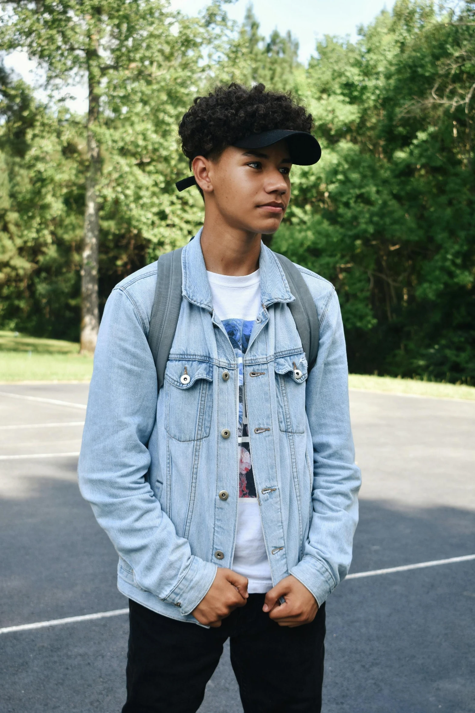 a young man standing on top of a tennis court, an album cover, pexels, realism, denim jacket, black teenage boy, headshot profile picture, with a backpack