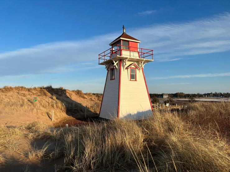 a red and white lighthouse sitting on top of a sandy beach, a photo, by Ryan Pancoast, square, lynn varley, cedar, former