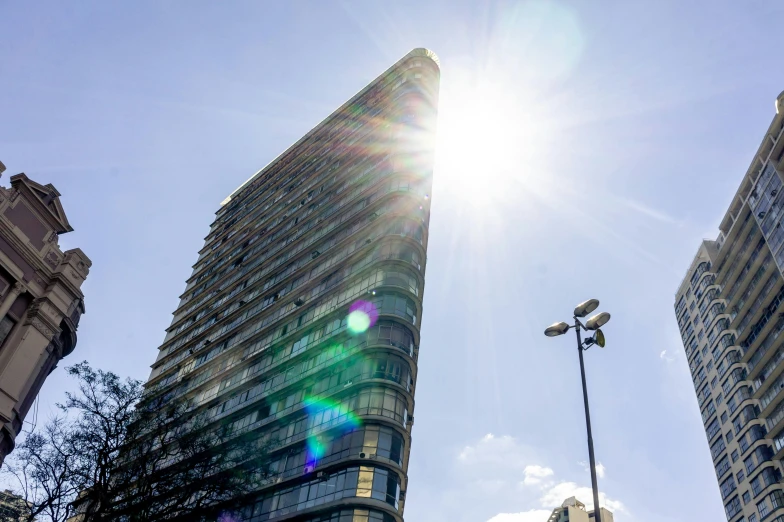 a group of tall buildings sitting next to each other, an album cover, inspired by Zaha Hadid, unsplash, sun flare, sparkling in the sunlight, james turrell building, seen from outside