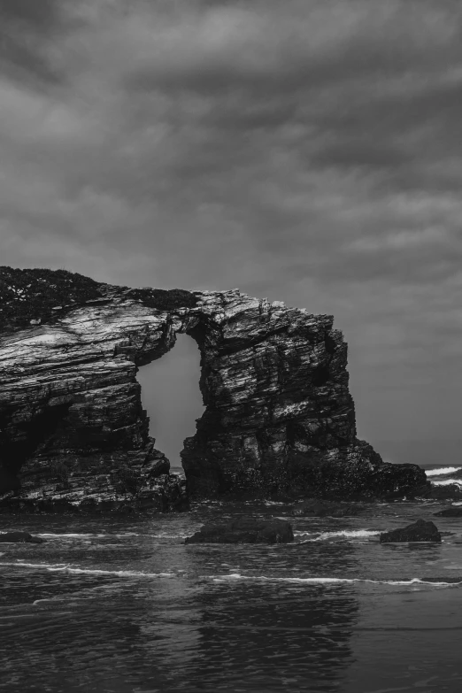 a black and white photo of a rock formation, inspired by Willem Claeszoon Heda, unsplash contest winner, an archway, south african coast, alvaro siza, aged and weathered