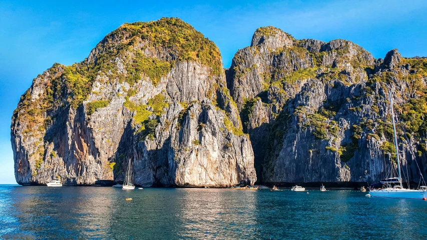 a group of boats floating on top of a body of water, pexels contest winner, sheer cliffs surround the scene, phong shaded, south east asian with round face, tessellated planes of rock